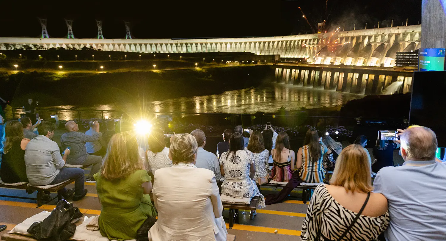Foto de pessoas assistindo iluminação da barragem da Usina Hidrelétrica de Itaipu, no Mirante Central.